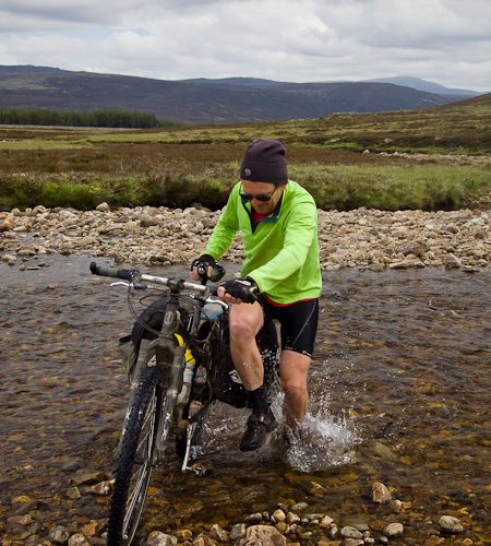Image of Reuben hopping across the Geldie Burn (in the Cairngorms) to keep one foot dry!